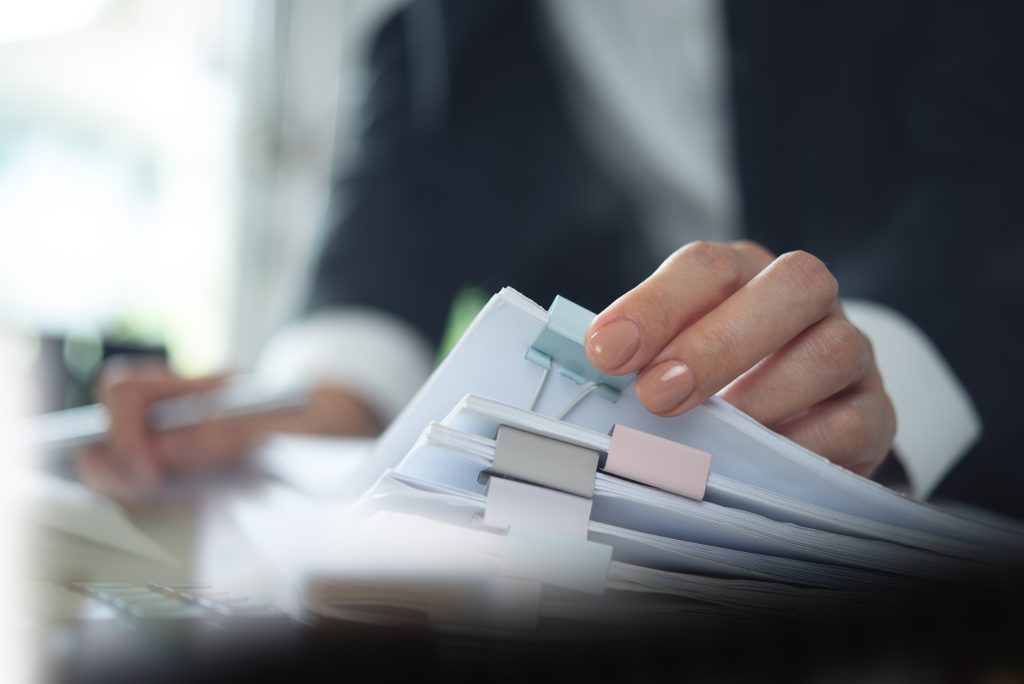 Handling a stack of neatly clipped documents in an school office setting.