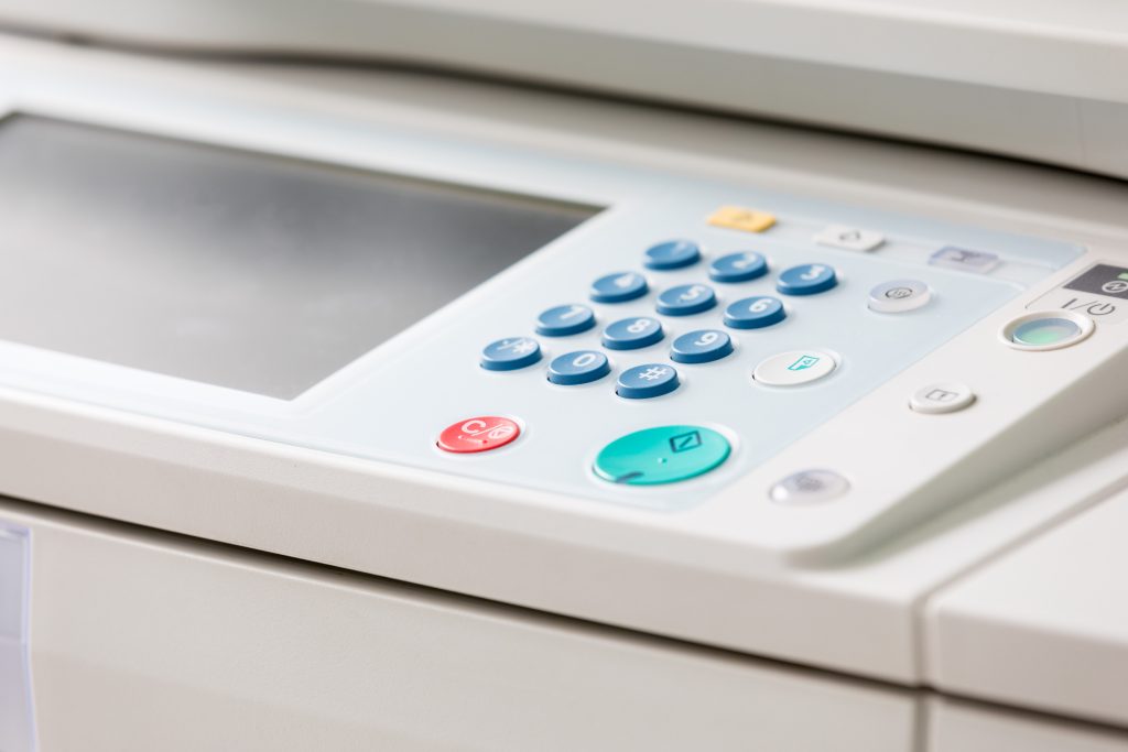 Close-up of a photocopying machine control panel with buttons and display screen.