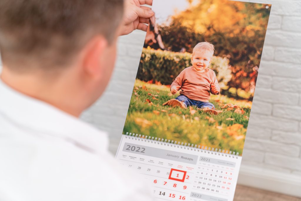 Person holding a personalised photo calendar featuring a smiling child, showcasing custom gift printing options in Croydon.