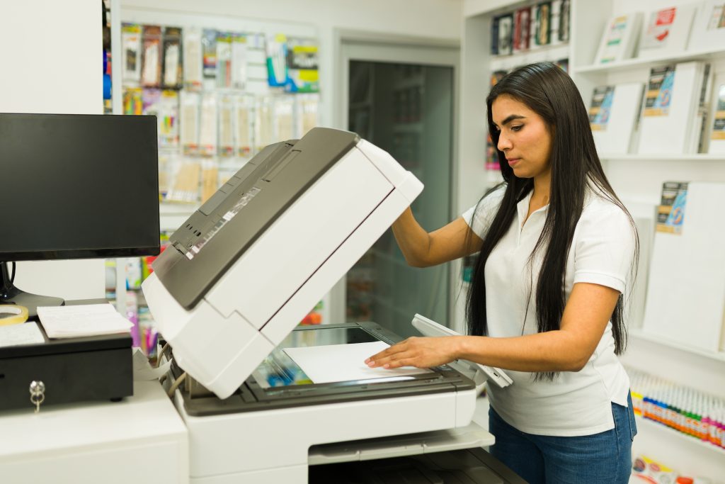 Professional print shop staff member using a high-quality photocopier to scan and print business documents.